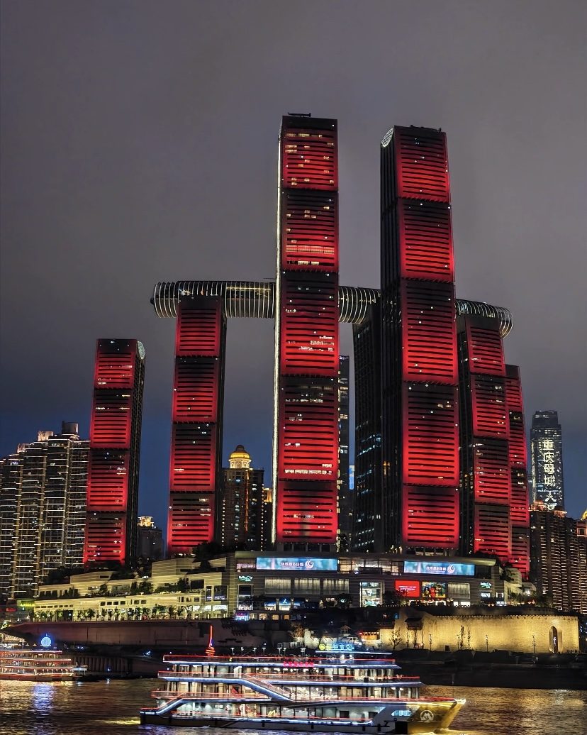 Chaotianmen towers lit red over the river at night